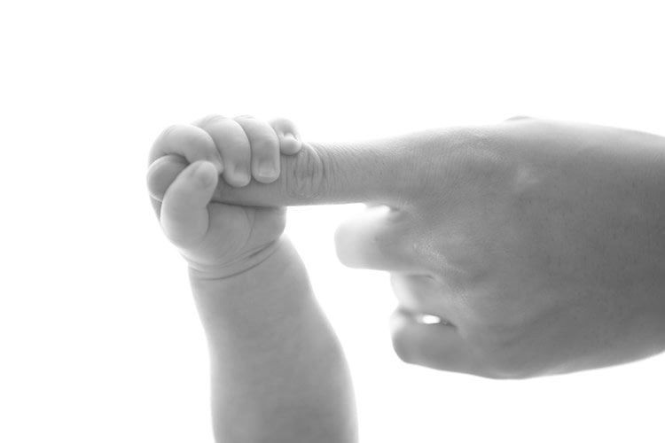 Image shows a dad holding a baby's hand.