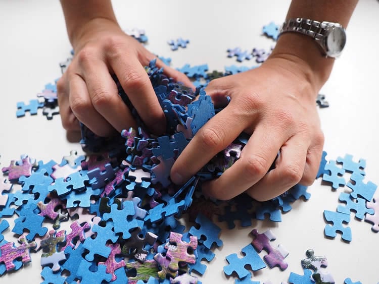 Image shows hands and jigsaw pieces.