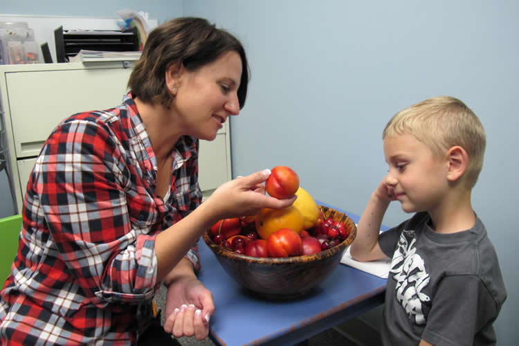 Image shows a mom and son eating a peach.