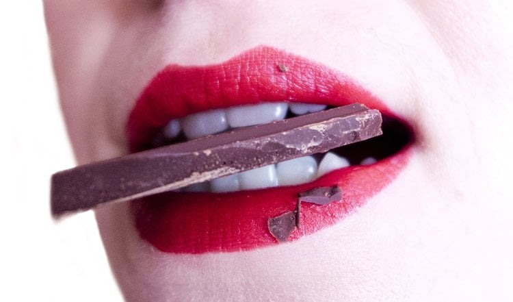 Image shows a woman eating chocolate.