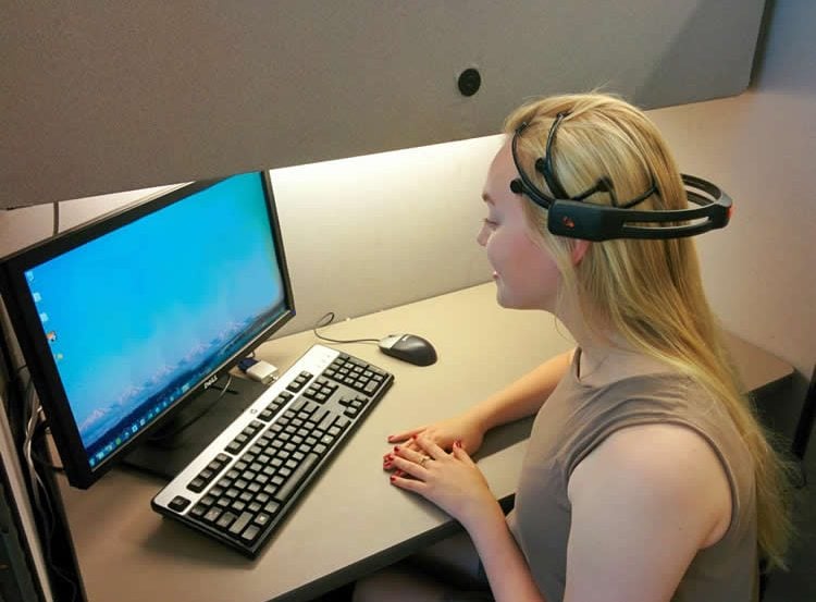 Image shows a woman in an EEG helm.