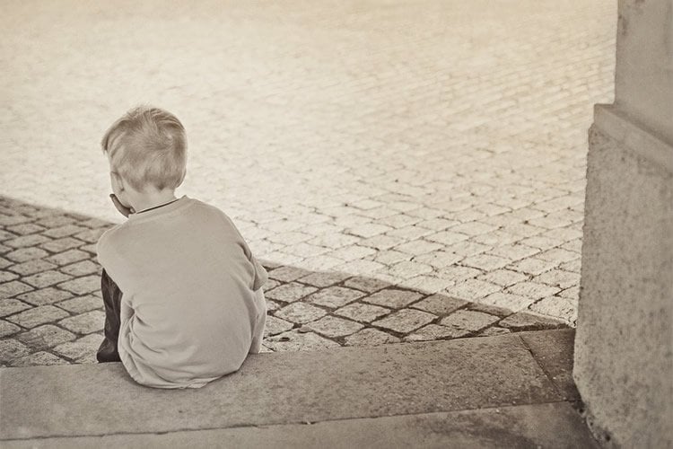 Image shows a young child sitting alone.