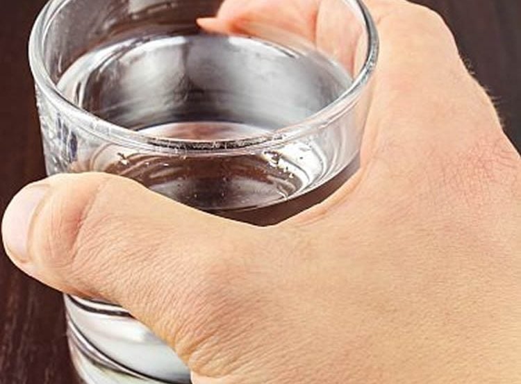 Image shows a hand grasping a cup.