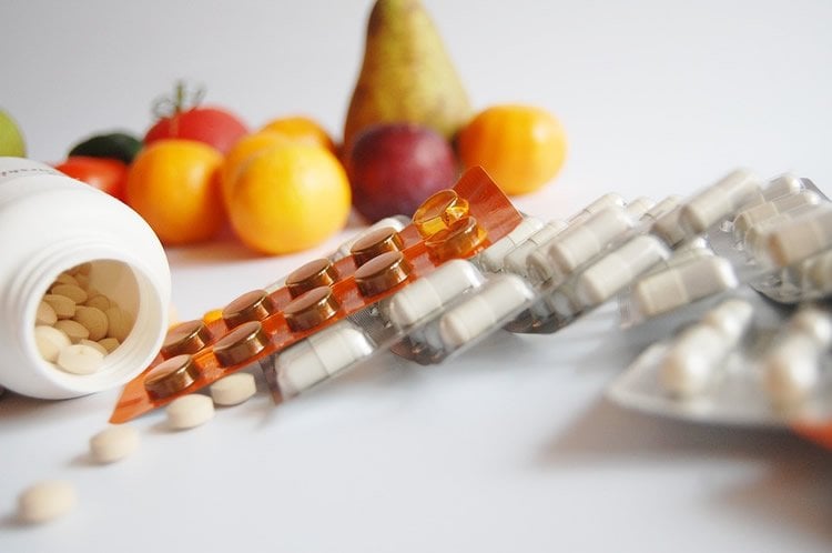 Image shows vitamin pills and fruits.