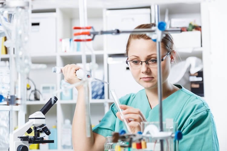 Image shows a woman performing an experiment in a lab setting.