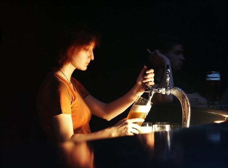 Image shows a woman serving beer.