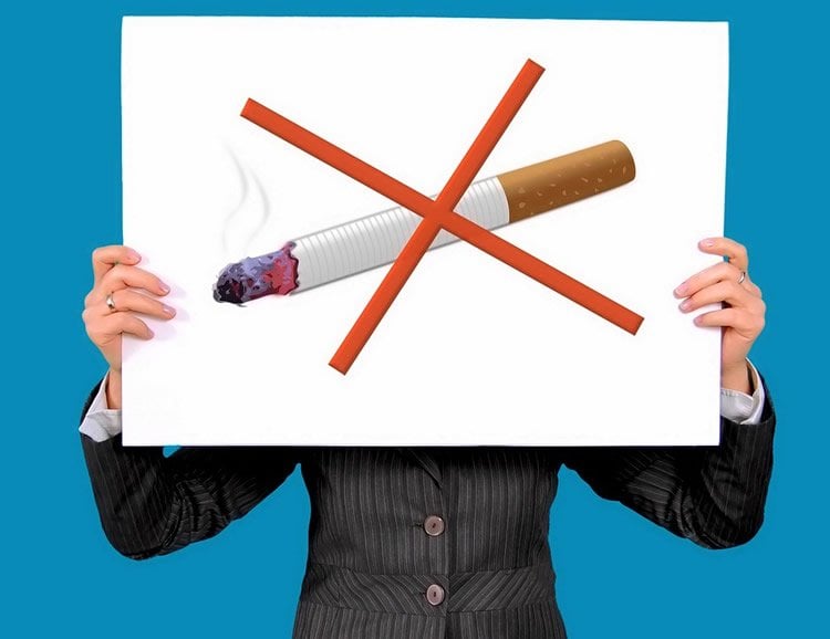 Image shows a person holding a no smoking sign.