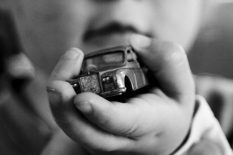 Image shows a little boy holding a toy car.