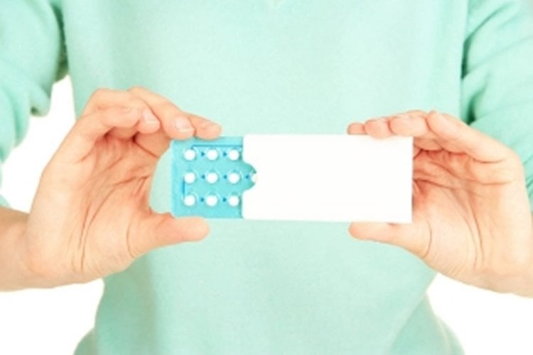 Image shows a woman holding pills.