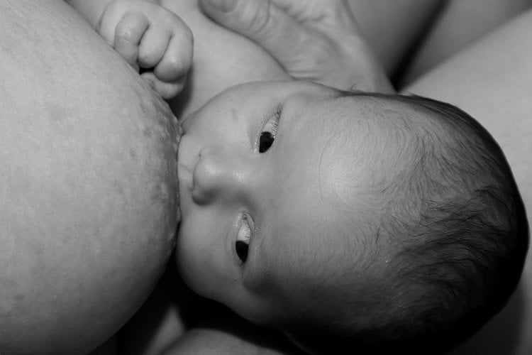 Image shows a baby breastfeeding.