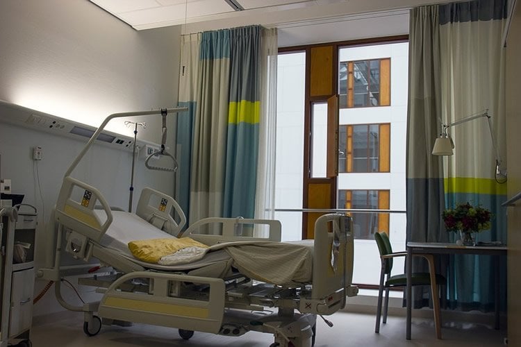 Image shows an empty hospital bed.