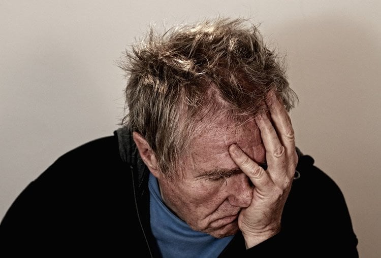 Image shows a depressed looking old man.