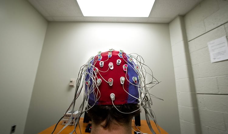 Image shows a person in an EEG cap.
