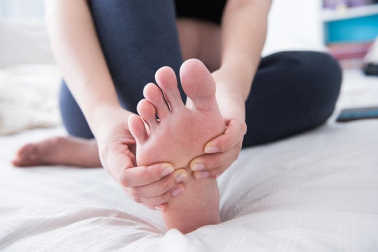 Image shows a person rubbing their foot.