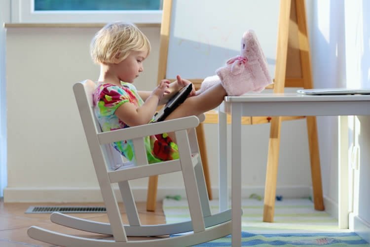 Image shows a little girl playing with a tablet.