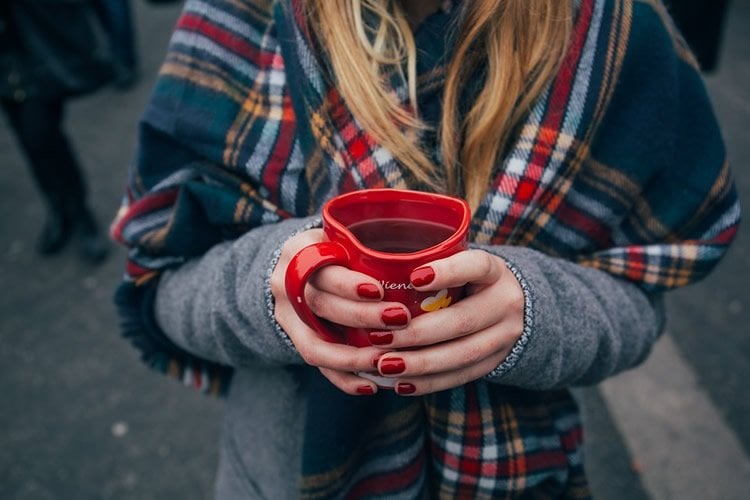 Image shows a woman holding a coffee cup.
