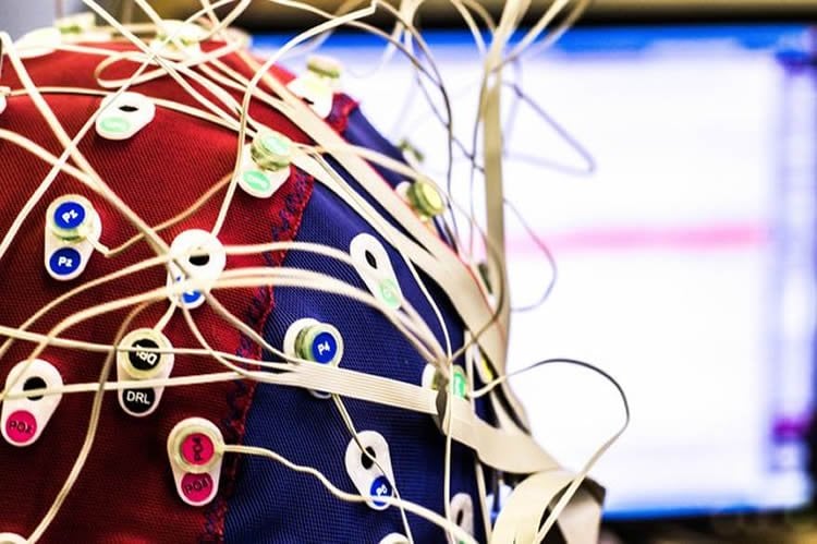 Image shows a person in an EEG cap.