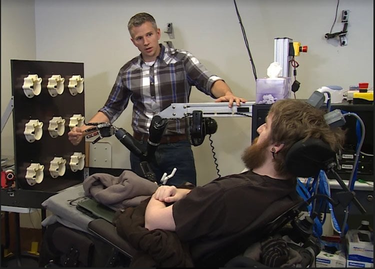 Image shows the patient using the robotic arm.