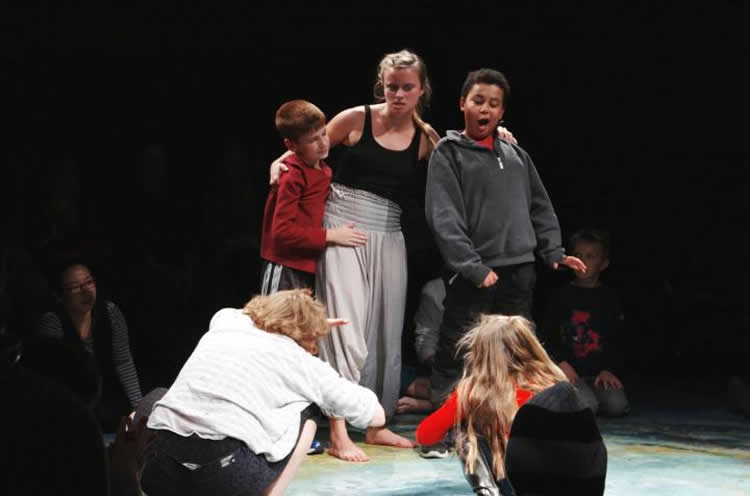 Image shows children performing a scene on a stage.