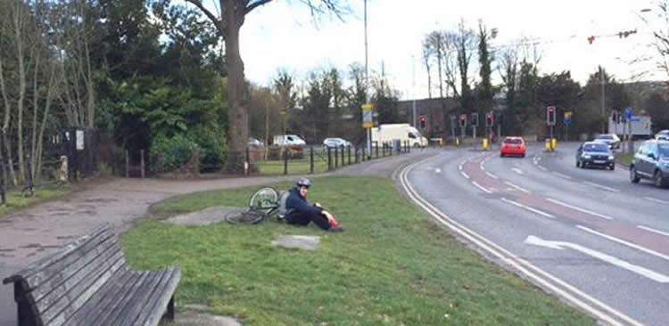 Image shows a person on the side of a road laying next to a bike.