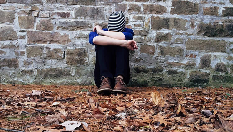 Image shows a person sitting next to a wall.