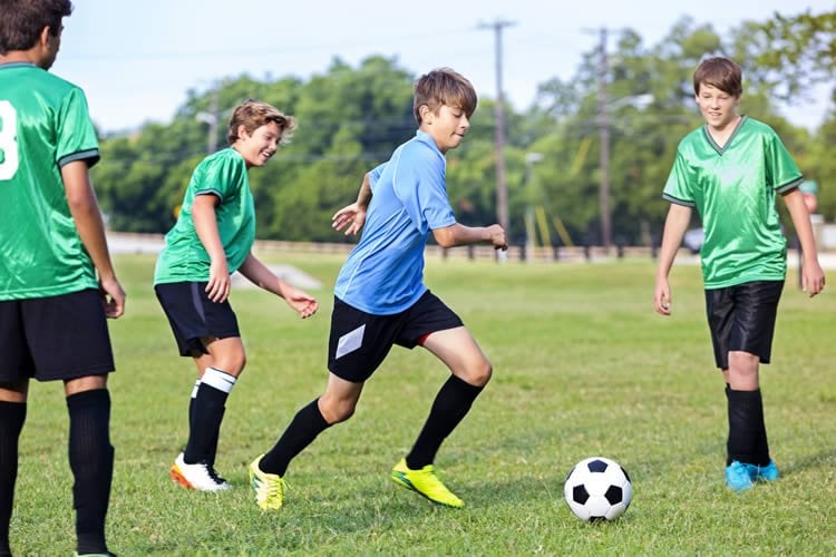 Image shows kids playing soccer.
