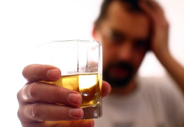 Image shows a man drinking whiskey.