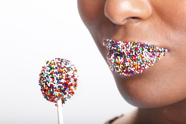 Image shows candy sprinkles on a woman's lips.