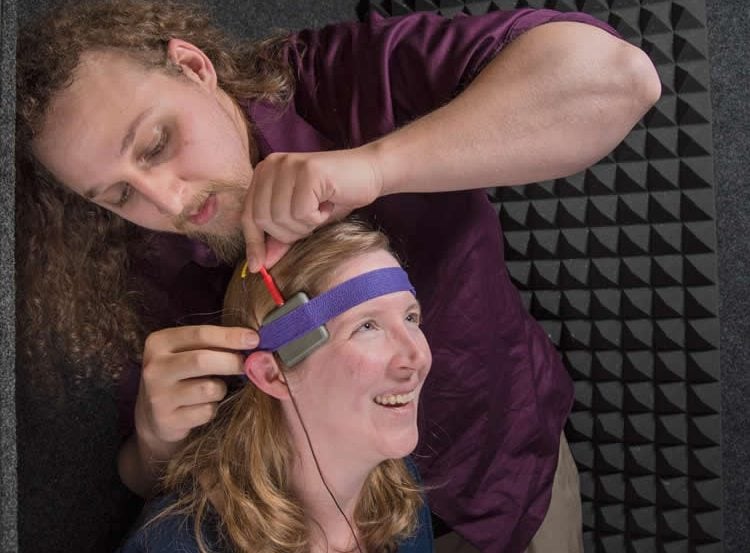 Image shows the researcher putting the tDCS machine on a subject's head.