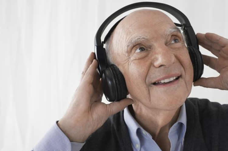 Image shows an old man listening to headphones.
