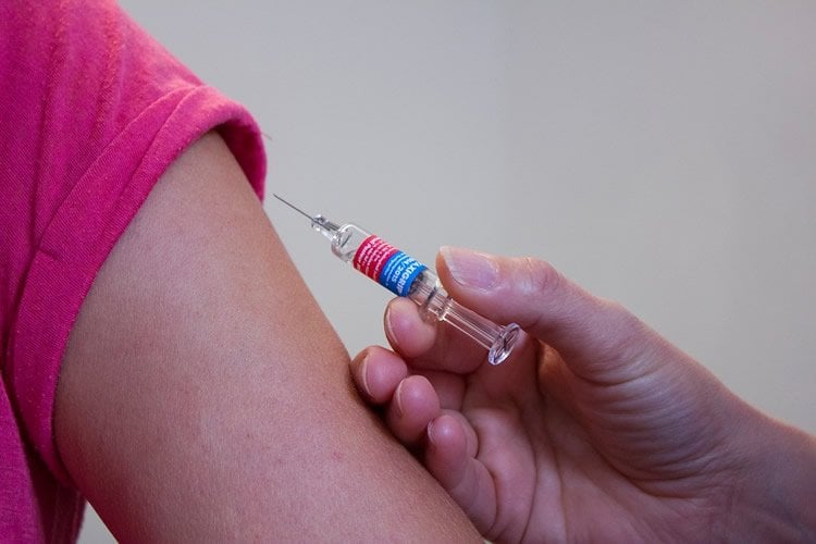 Image shows a person receiving a vaccine.