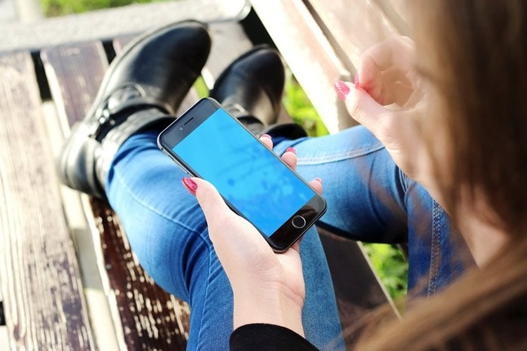 Image shows a woman playing with a smartphone.