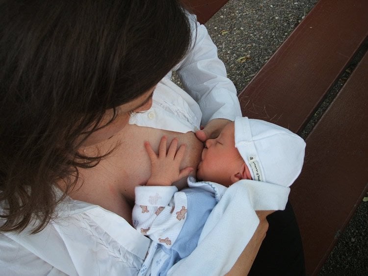 Image shows a woman breastfeeding a newborn.