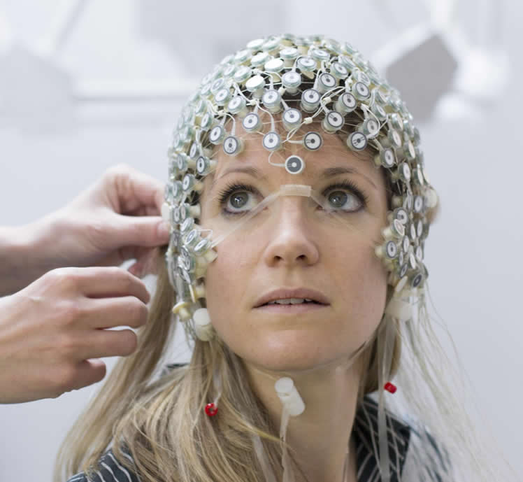 Image shows a woman in an EEG cap.