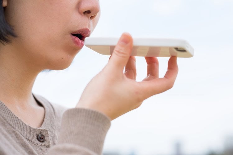 Image shows a person talking to their phone.