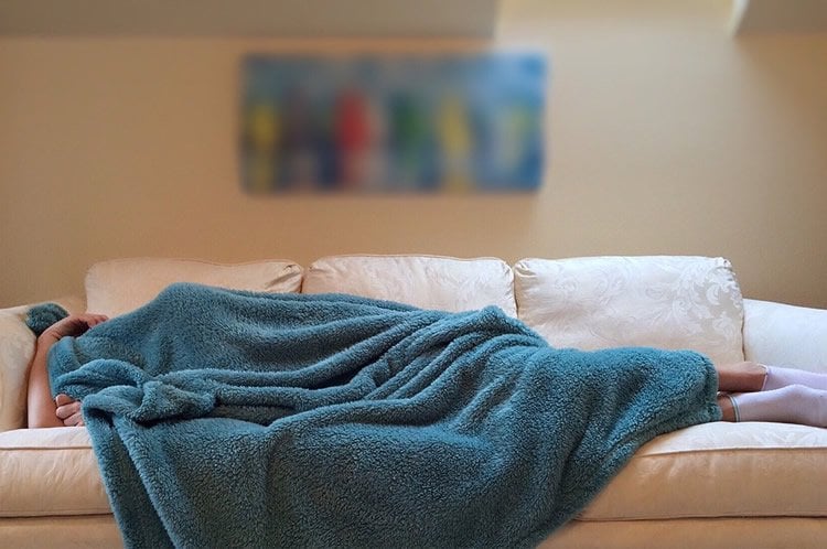 Image shows a person sleeping on a couch.