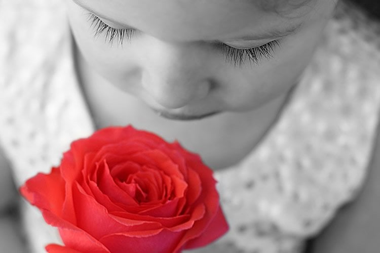 Image shows a girl sniffing a rose.