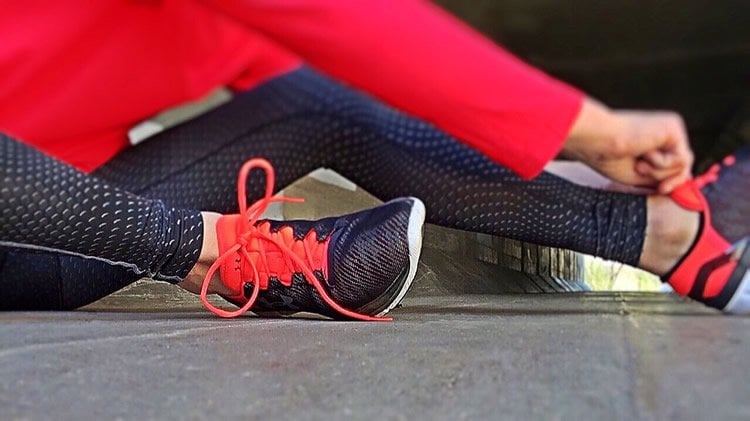 Image shows a person lacing up running shoes.