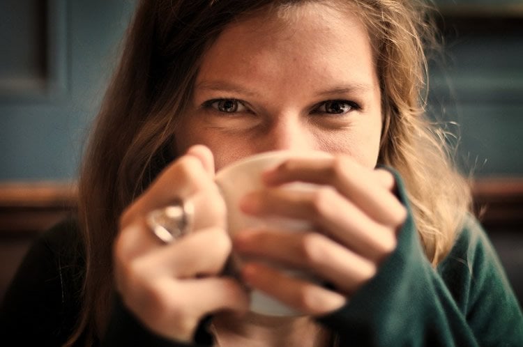 Image shows a woman drinking coffee.