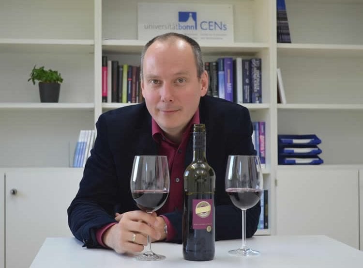 Image shows the professor and two glasses of red wine.