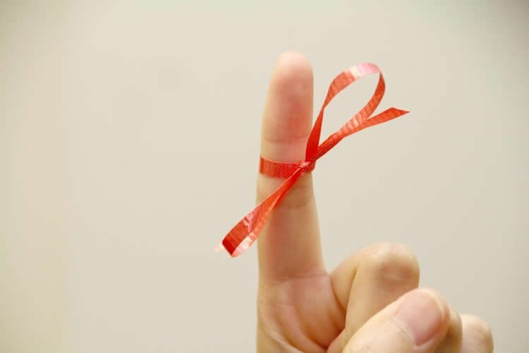 Image shows a finger with a bow tied on it.