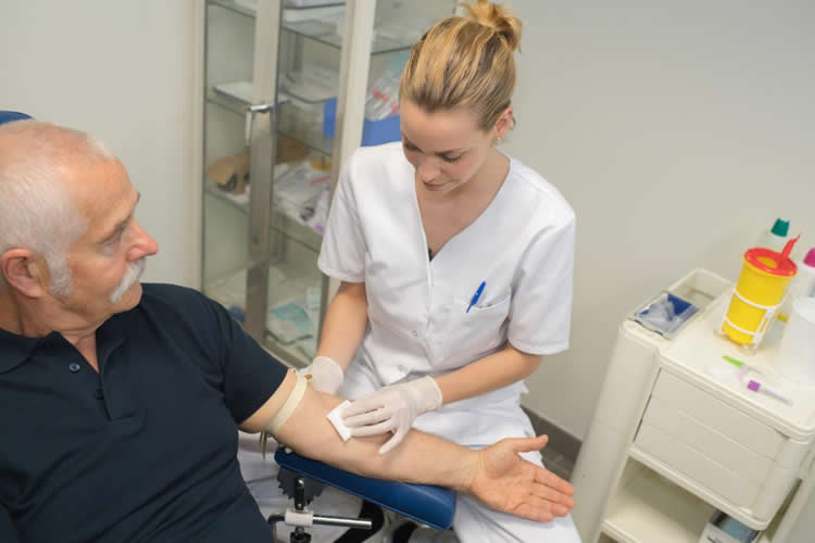 Image shows a nurse drawing blood from an older man.