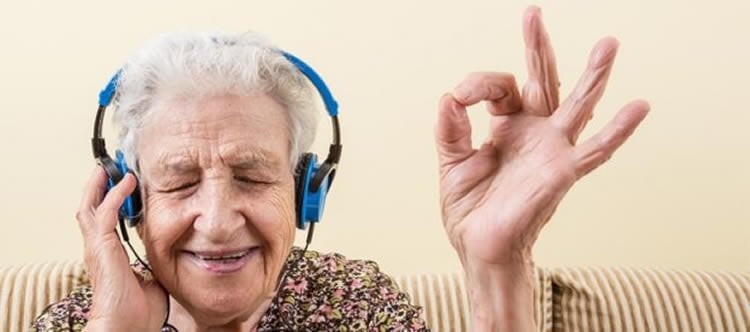 Image shows an old lady listening to music.