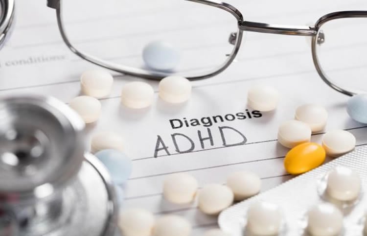 Image shows a pills and paper with "Diagnosis: ADHD" written on it.