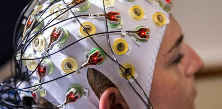 Image shows a person in an EEG cap.