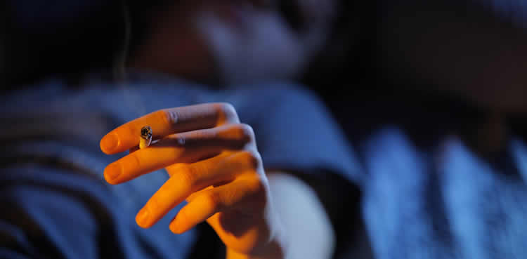 Image shows a person smoking while resting.