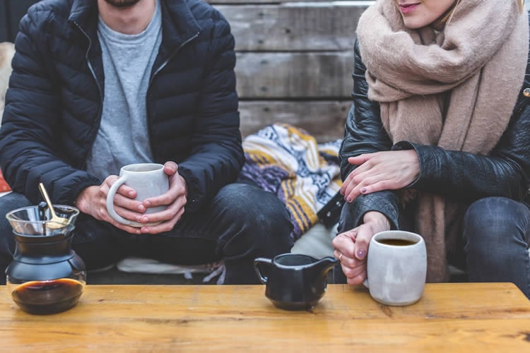 Image shows a couple drinking coffee.