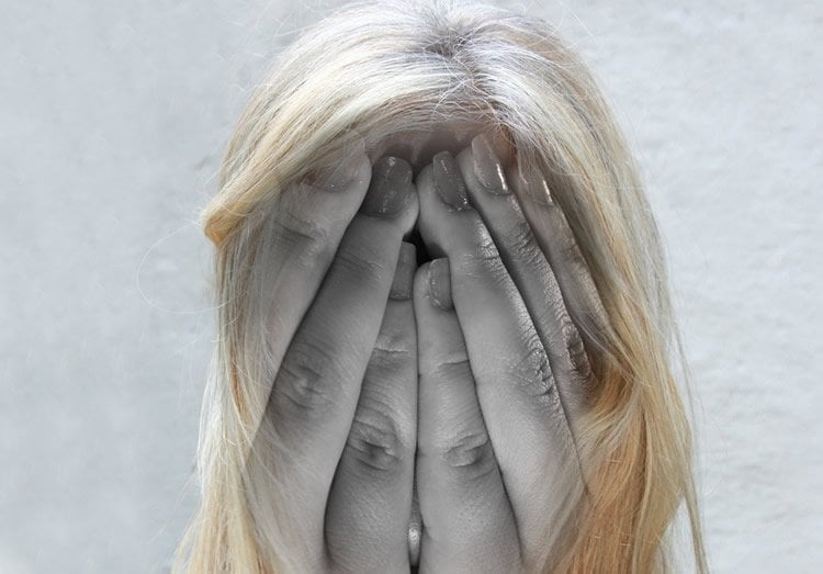 Image shows a woman holding her head.