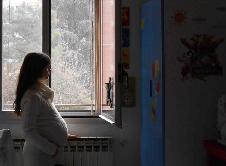 a pregnant woman is looking through a window in this image.