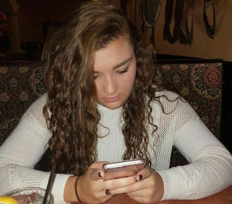 Image shows a teen using a smartphone.